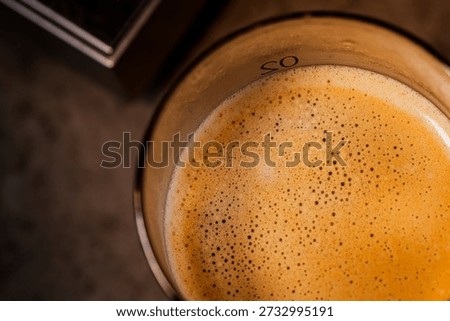 Through extremely close-up macro photography, the delicate bubbles of coffee crema and the glistening water droplets on the surface of a cold drink glass are captured, creating a warm and sophisticated afternoon atmosphere.