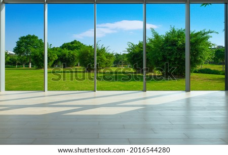 Through the floor-to-ceiling windows, the green grass and woods of the city park
