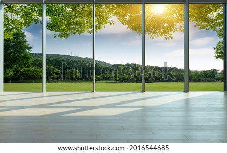 Through the floor-to-ceiling windows, the green grass and woods of the city park