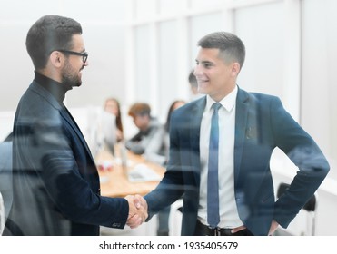 through the glass. business partners handshake in the office - Shutterstock ID 1935405679