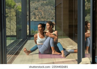 Through glass of female with closed eyes practicing Marichyasana with instructor sitting behind in villa - Powered by Shutterstock