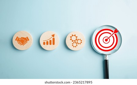 Through the magnifying glass, a businessman focuses on the target goal icon, illustrating the essential strategies, corporate development, and global business leadership for success in the industry. - Shutterstock ID 2365217895