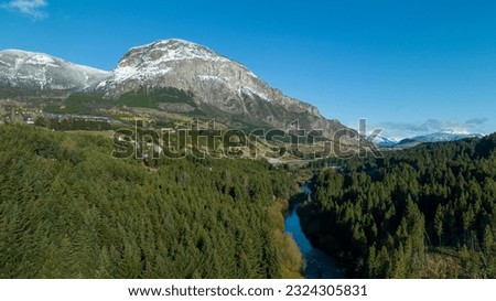 Through native forests, it crosses the Simpson River. Behind you can see the imposing snow-capped Mackay hill in the middle of mountain ranges of the Andes Mountains. City of Coyhaique, Chile.