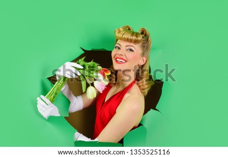 Through paper. Smiling woman through paper. Pin up woman. Looking through paper. Pin up woman holds bouquet . Bouquet of flowers. Breaking wall. Sale. Discount. Spring flowers. Advertising.