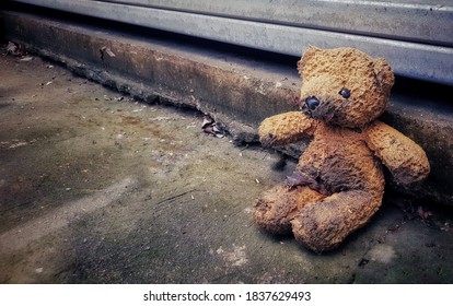 throw away old Dirty brown Teddy bear doll sitting alone and lonely out side of the house in side the road.international missing children's day concept.