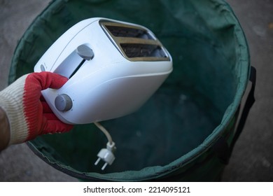 Throw away old kitchen appliances. Disposal of electrical appliances in the trash. Find it in the trash. Throw the bread toaster in the trash. - Shutterstock ID 2214095121