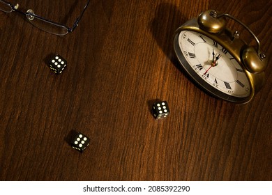 a throw of black dice on a wooden table next to an old clock showing almost 12 o'clock