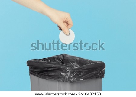 throw a cap from a plastic bottle into the trash bin, hold a cap from a plastic bottle in your hand in front of a trash can, plastic recycling concept