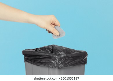 throw mediator for disassembling phones and laptops into trash can, mediator in hand in front of trash can, plastic recycling concept