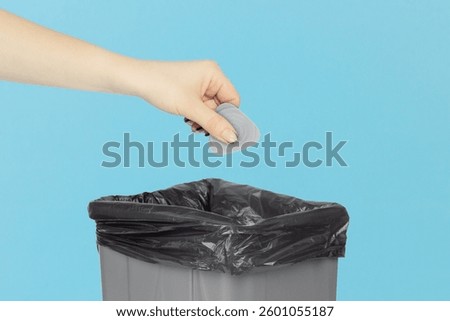 throw mediator for disassembling phones and laptops into trash can, mediator in hand in front of trash can, plastic recycling concept