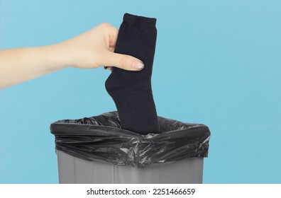 throw socks in the bin, a pair of socks in the hand in front of the bin, the concept of dirty shoes and smelly socks