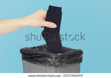 throw socks in the bin, a pair of socks in the hand in front of the bin, the concept of dirty shoes and smelly socks
