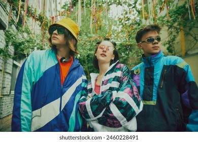 Throwback fashion. Stylish boys and girl wearing typical 90s outfits, tracksuits and accessories, posing outdoors. Vintage athletic wear. Concept of 90s, fashion, youth culture, old-style trends