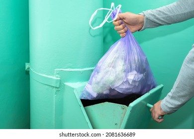 Throwing garbage into the garbage chute, a man's hand with a garbage bag.
