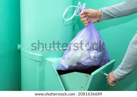 Throwing garbage into the garbage chute, a man's hand with a garbage bag.