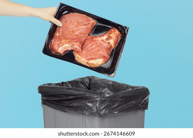 throwing marinated steak in vacuum packaging into the trash, reaching hand with marinated steak in vacuum packaging to trash can, vegetarianism concept
