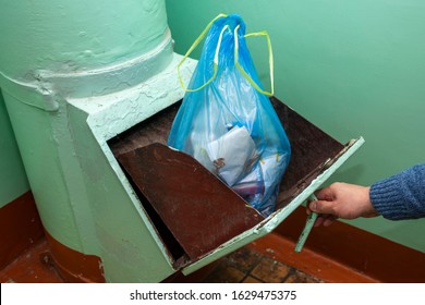 Throwing Out Garbage Packed In A Garbage Bag Using A Home Trash Chute In Russia. Refuse Chute