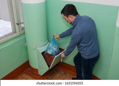 Throwing Out Garbage Packed In A Garbage Bag Using A Home Trash Chute In Russia. Refuse Chute