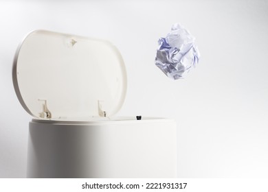 Throwing A Paper Ball Into A White Plastic Garbage Bin