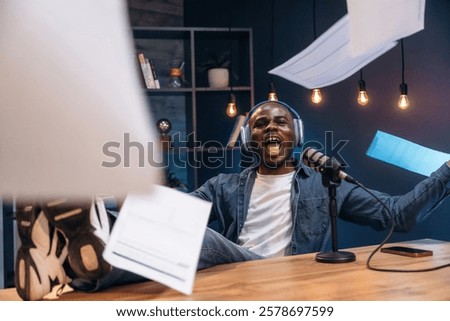 Throwing papers up. Man is doing podcast in the studio.