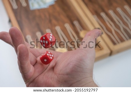 Throwing  red dice in the air. Hand throws the dice on the background of Board games(backgammon). Selective focus. Known as 'tavla' in Turkish