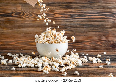 Throwing Of Tasty Popcorn Into Bowl On Wooden Background