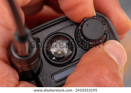 thumb and forefinger of a white man's human hand turning a black plastic button.
