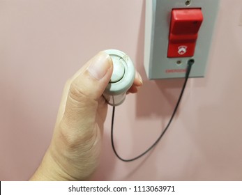 A thumb is going to press the button for emergency case in the toilet for patient. Health care and first aid concept.