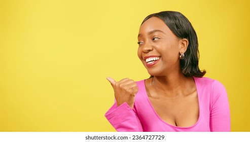 Thumb pointing back at copy space, beautiful Black woman, yellow studio - Shutterstock ID 2364727729