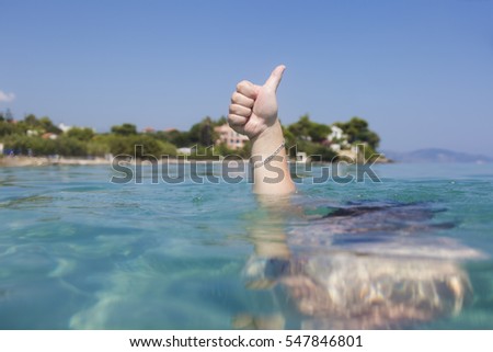 Thumb up sign from underwater in ionian sea, Zakynthos island, Greece. concept of successful summer hollidays