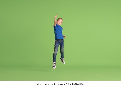 Thumb Up. Happy Boy Playing And Having Fun On Green Studio Background. Caucasian Kid In Bright Cloth Looks Playful, Laughting, Smiling. Concept Of Education, Childhood, Emotions, Facial Expression.