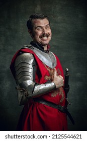 Thumb Up. Portrait Of Smiling Man In Image Of Medieval Warrior With Wounded Face Wearing Equipment Isolated Over Dark Background. Comparison Of Eras, History, Renaissance Style. Funny Meme Emotions