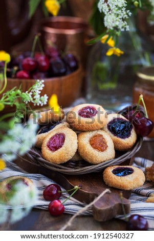 Thumbprint almond cookies with jam on rustic wooden background