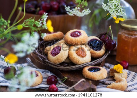 Thumbprint almond cookies with jam on rustic wooden background