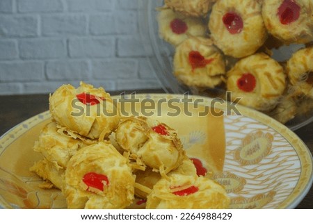 Thumbprint Cookies, made with butter, flour, baking powder, sugar and vanilla. With filling strawberry Paste and grated cheese sprinkles. Typical delicacy for Eid Al Fitr and Christmas