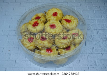Thumbprint Cookies, made with butter, flour, baking powder, sugar and vanilla. With filling strawberry Paste and grated cheese sprinkles. Typical delicacy for Eid Al Fitr and Christmas