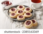 Thumbprint or Hallongrottor Swedish Raspberry Jam Cookies closeup on the plate on the white wooden table. Horizontal
