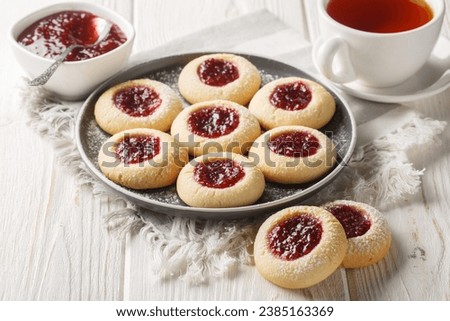 Thumbprint or Hallongrottor Swedish Raspberry Jam Cookies closeup on the plate on the white wooden table. Horizontal
