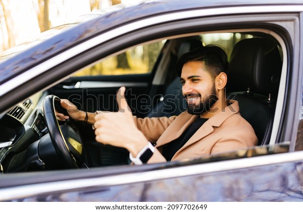 Thumbs up. Portrait of a happy businessman\
showing thumbs up sitting in his new\
car