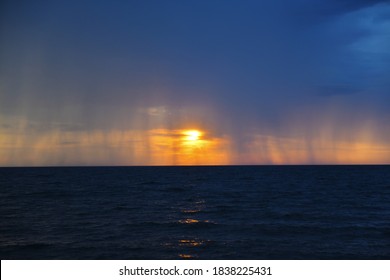 Thundercloud and streams of rain against the setting sun over the Mediterranean Sea. Foamy surf on the shore. Tropical downpour. Seascape. - Powered by Shutterstock - Get 15% off with code: PIKWIZARD15