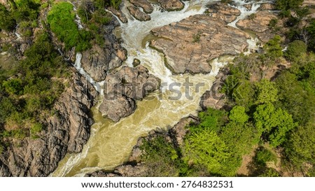 The thundering rapids of Li Phi Waterfall cut across the Mekong River, creating dramatic torrents, misty spray, and a striking tropical landscape from above.