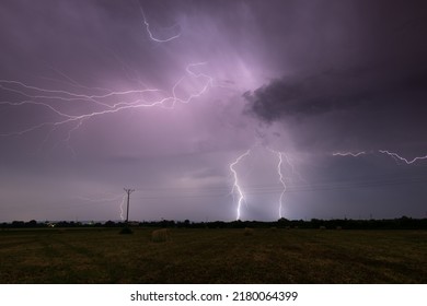 Thunderstorm above field with roll bales of hay at night, cloud to ground branched lightning, lightning in clouds at night in countryside - Powered by Shutterstock