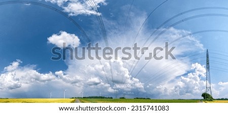 a thunderstorm moving across the countryside with wispy clouds in the sky and agricultural fields on the ground and overhead power lines or high-voltage power lines with electricity pylons and rotor b