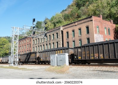 Thurmond, West Virginia US - October  10,  2021: Traffic Signal High Above Tracks  With Historic Buildings Behind Loaded Coal Train Cars Ready To Depart To  Power Plant Destination  Delivery