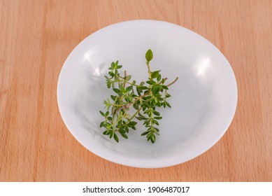 Thyme leaf herb in a white bowl placed on a wooden chopping board ingredients
