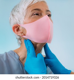 Thyroid Gland Medical Exam. Endocrinologist Examining Nack Of A Senior Woman With Thyroid Disease Symptoms. Wearing Protective Mask.  