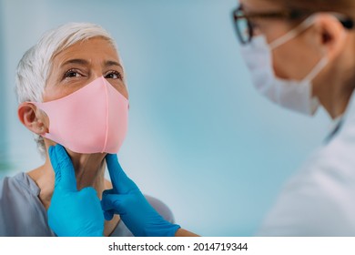 Thyroid Gland Medical Exam. Endocrinologist Examining Nack Of A Senior Woman With Thyroid Disease Symptoms. Wearing Protective Mask.  