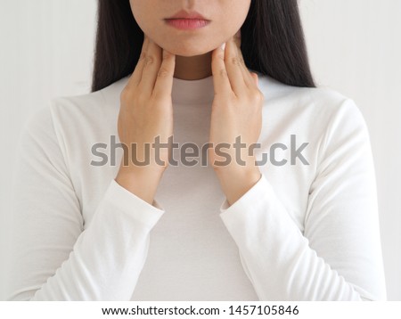 thyroid gland,hyperthyroidism and tonsillolith or tonsil stones and laryngeal cancer in asian woman. She use hand touching neck on isolated white background using for health care concept.