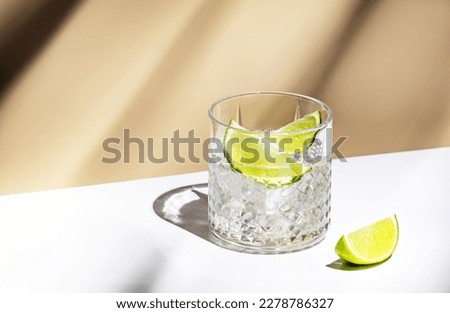 Ti punch alcoholic cocktail drink with white rum agricole, sugar syrup and lime, traditional Caribbean beverage. Beige background, minimalist style