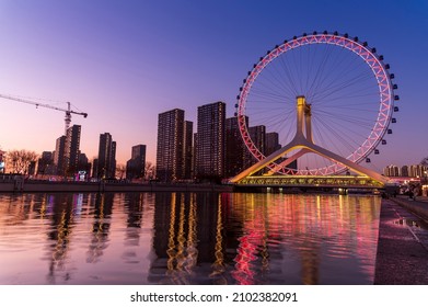 Tianjin ferris wheel or Tianjin eyes and  waterfront downtown skyline with Tianjin high-rise building cityscape at Haihe riverside, Tianjin city, China in Sunset twilight scene.